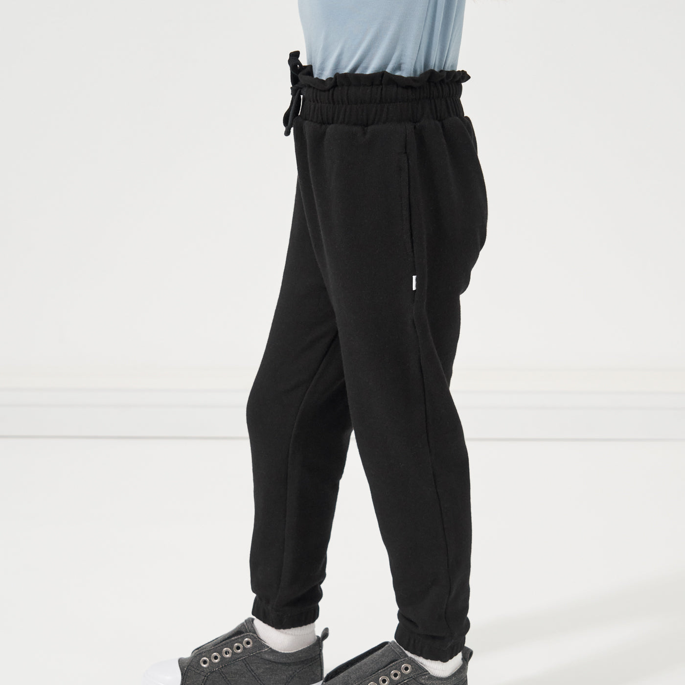 Close up profile image of a child wearing Black Paperbag Joggers paired with a Fog Classic Tee