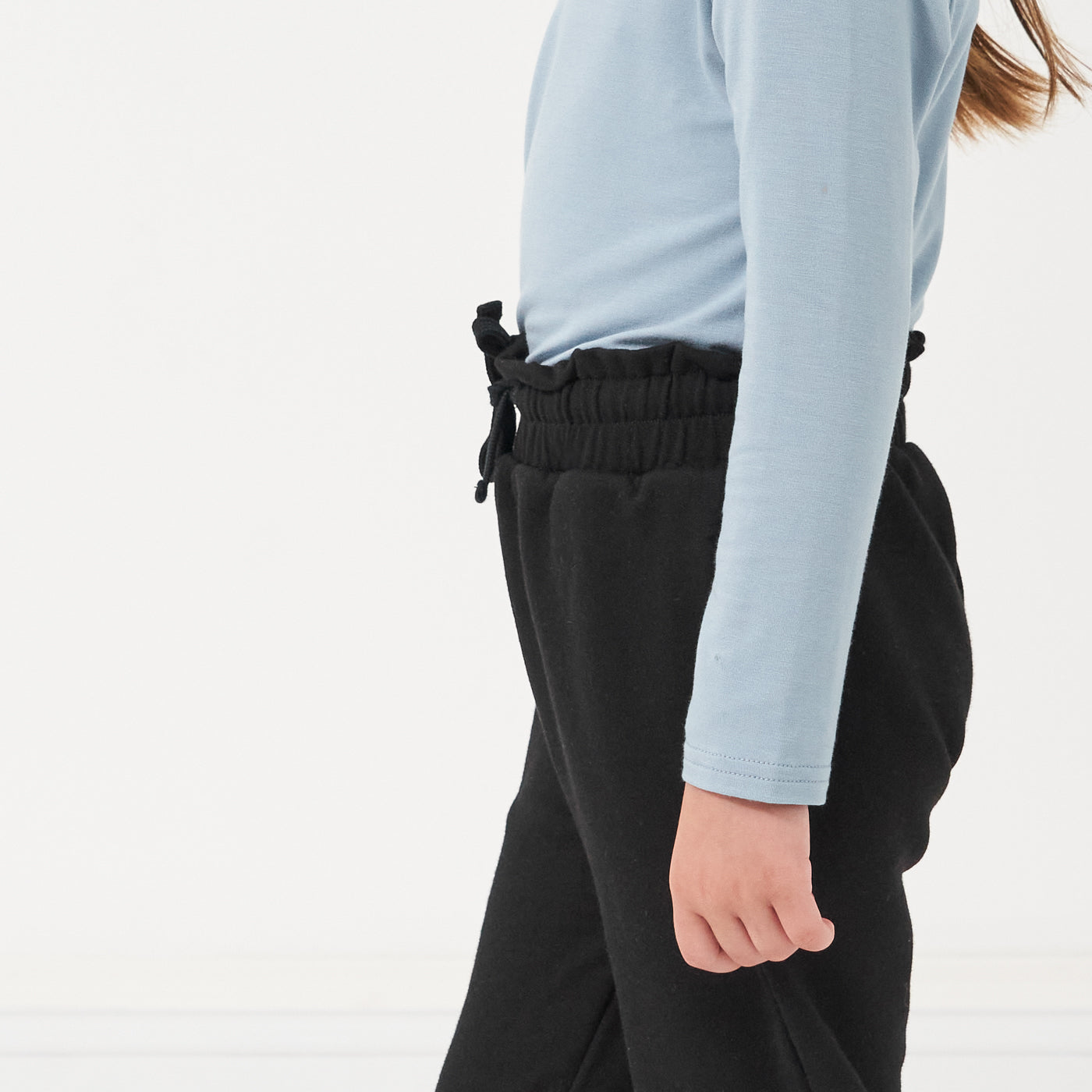 Close up profile image of a child wearing Black Paperbag Joggers paired with a Fog Classic Tee detailing lettuce hem
