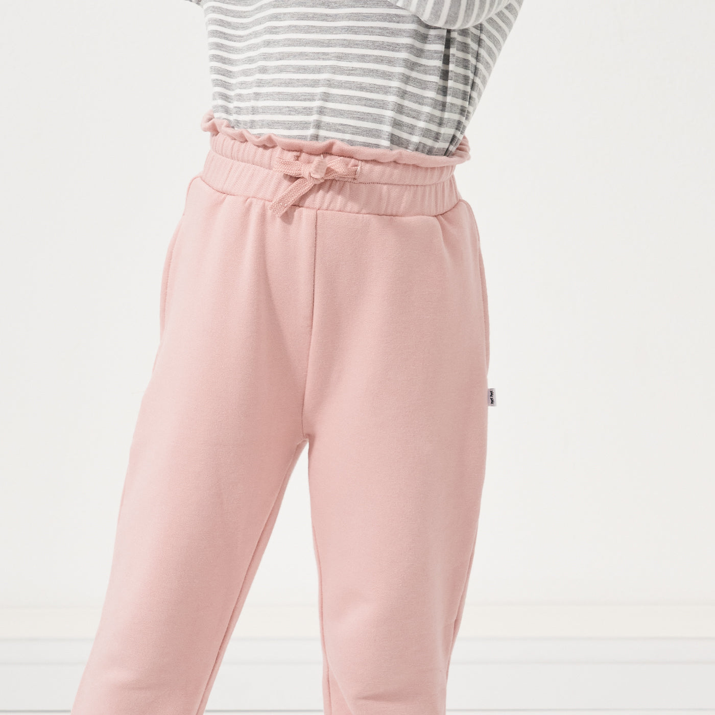 close up image of a child wearing Mauve Blush Paperbag Joggers and a Fog and Ivory Striped classic tee focusing on the drawstring waist of the paperbag joggers