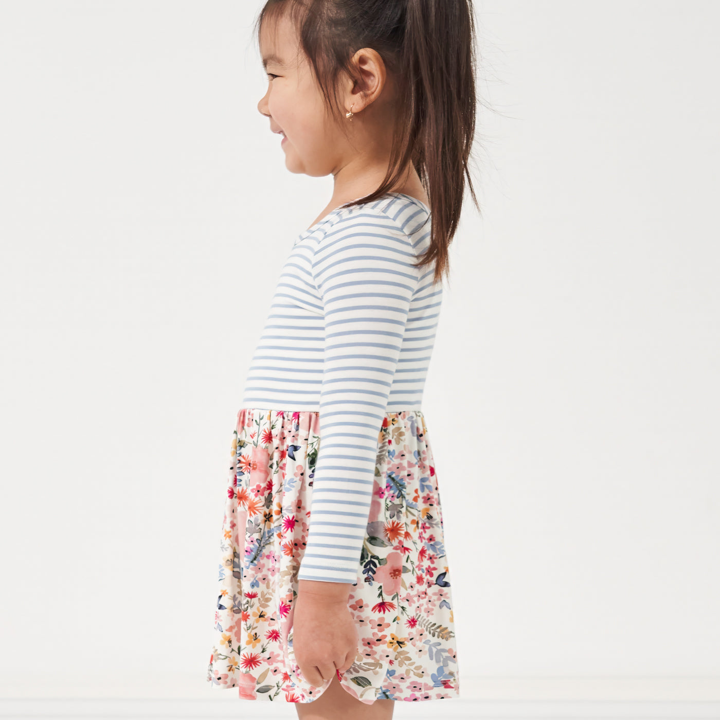 Profile view of a child wearing an Ivory and Fog and Mauve Meadow skater dress with bodysuit