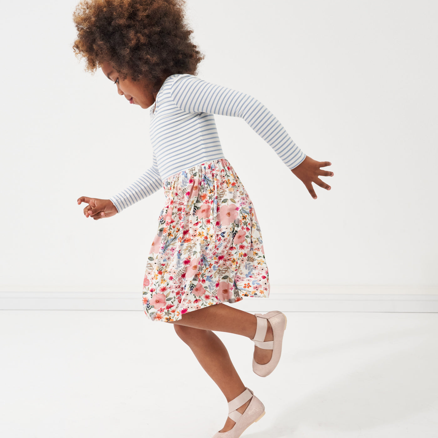 profile view of a child running wearing an Ivory and Fog Stripe and Mauve Meadow skater dress