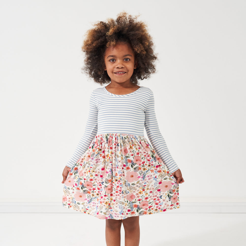 Click to see full screen - Child posing wearing an Ivory Fog Stripe and Mauve Meadow skater dress