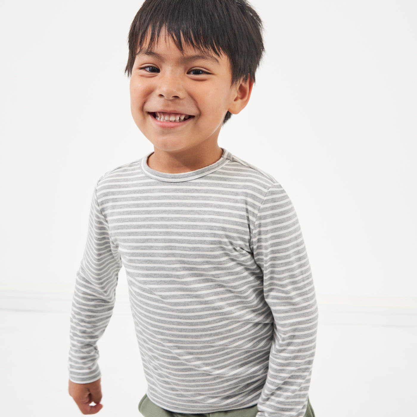 Child playing wearing a Heather Gray and Ivory Stripe classic tee paired with Moss joggers