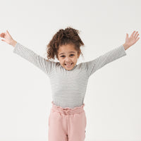 Child posing wearing a Heather Gray and Ivory Stripe classic tee paired with Mauve Blush paperbag joggers