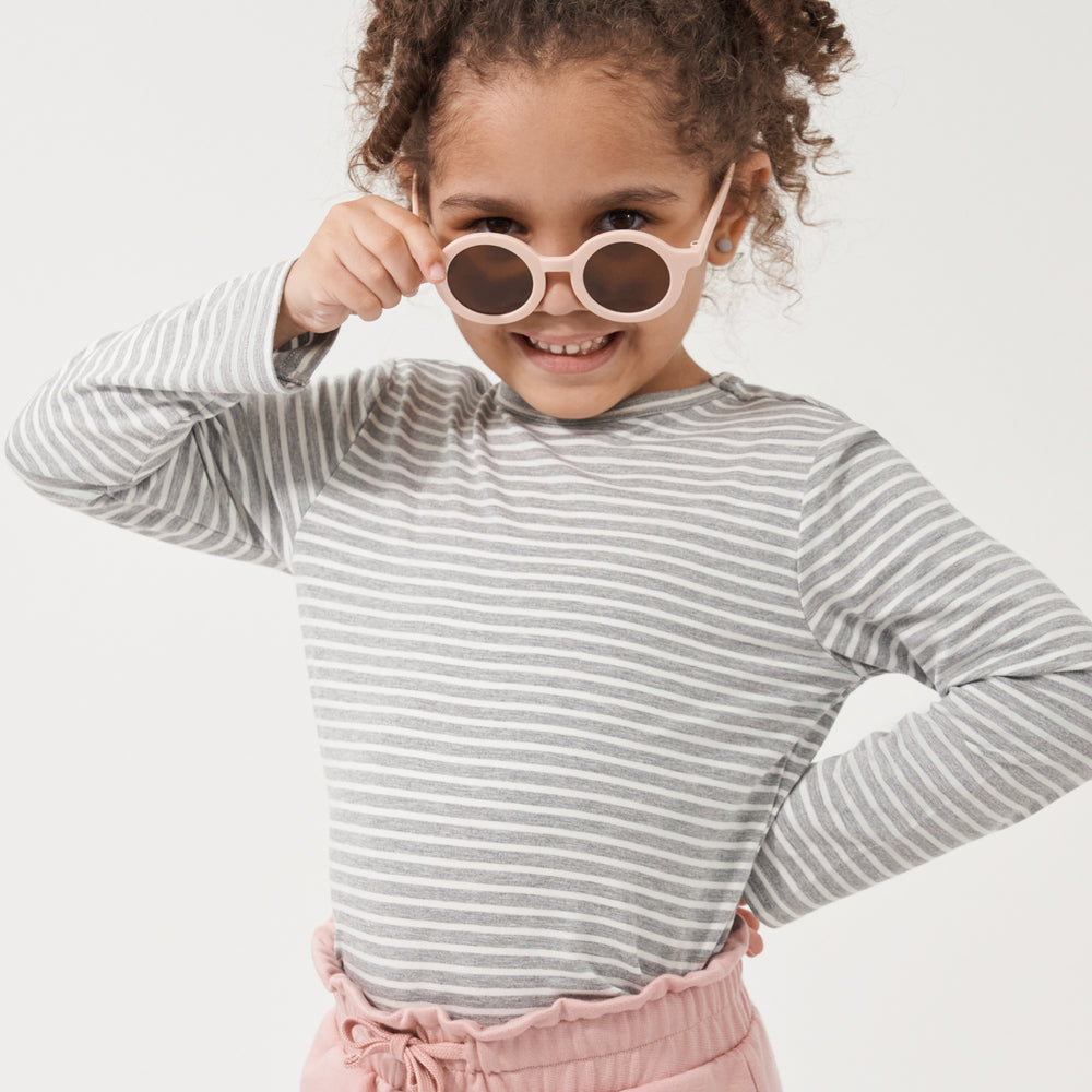 Child posing with sunglasses wearing a Heather Gray and Ivory Stripe classic tee paired with Mauve Blush paperbag joggers