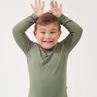 Child with his hands over his head wearing a Moss classic tee