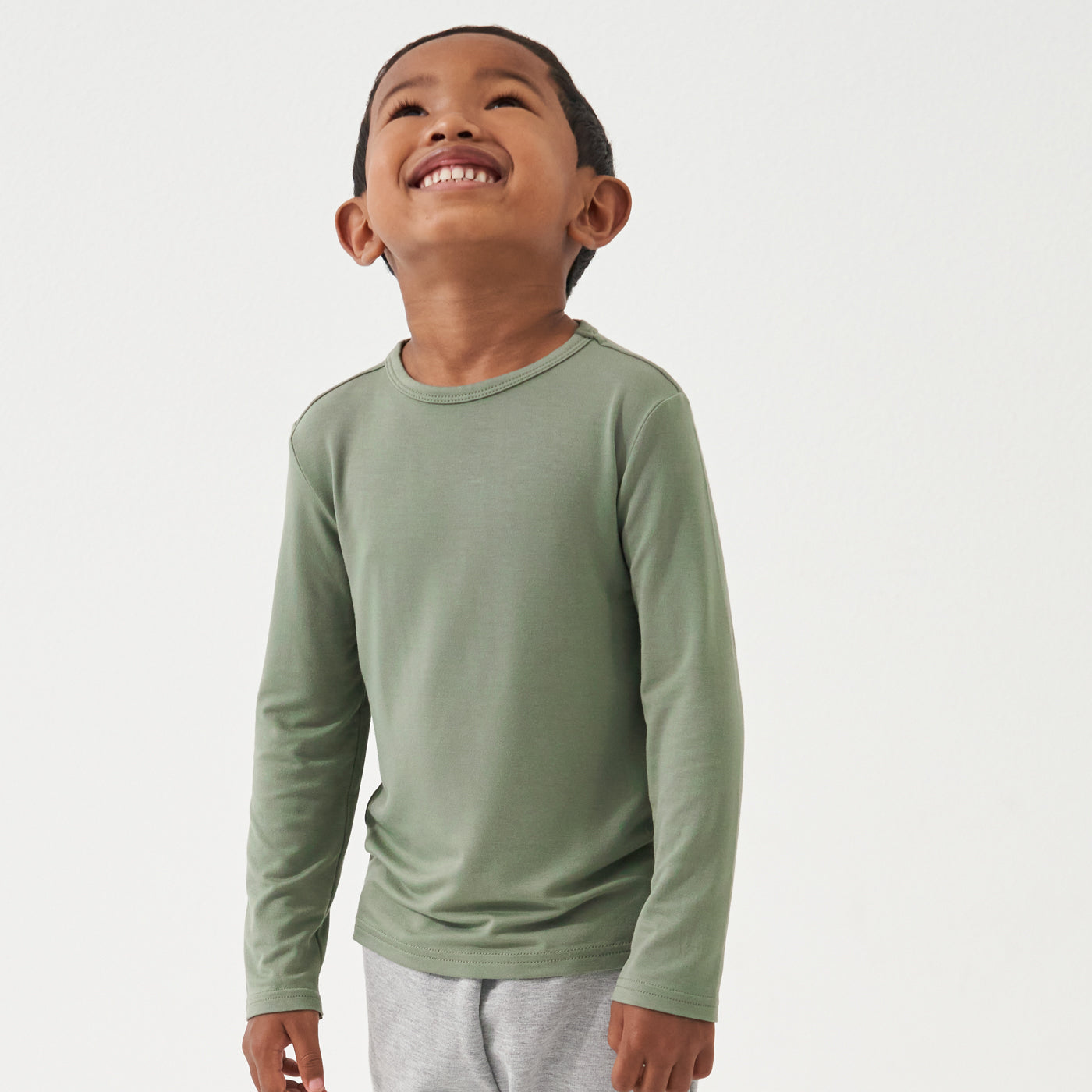 Child looking up and laughing wearing a Moss classic tee