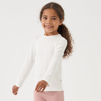 Child twirling wearing an Ivory classic tee paired with Mauve leggings