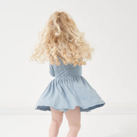 Back view image of a child spinning around wearing a Fog twirl dress with bodysuit