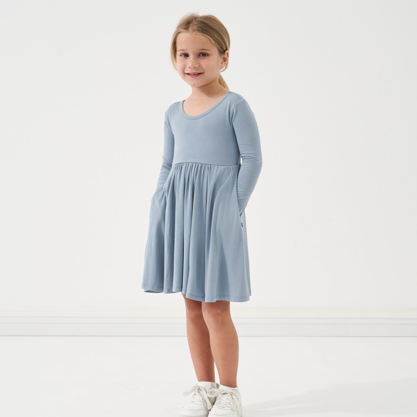 Child with her hands in her pockets wearing a Fog twirl dress