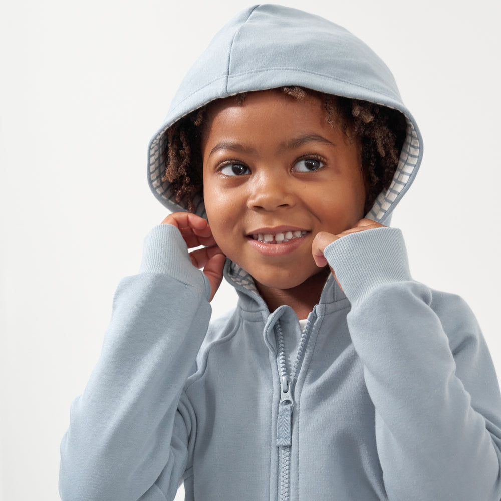 Click to see full screen - Close up image of a child wearing a Fog zip hoodie with the hood over their head