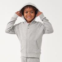 Child wearing a Heather Gray zip hoodie with the hood on