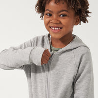 Close up image of a child zipping up their Heather Gray zip hoodie