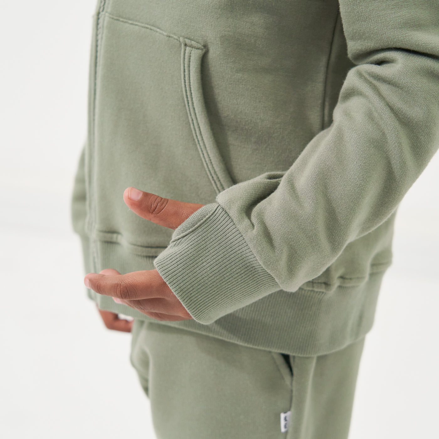 Close up image of a child wearing a Moss zip hoodie detailing the thumb hole in the sleeve cuff