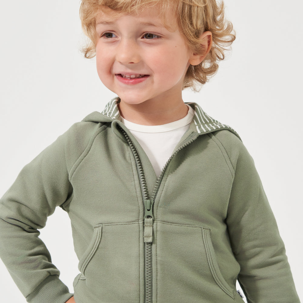 Close up image of a child wearing a Moss zip hoodie