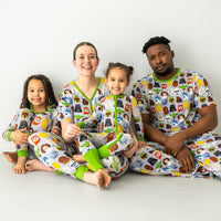 Family of four sitting on the ground wearing matching Legends of the Galaxy pajamas