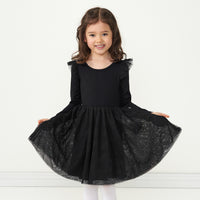 Child wearing and holding out the sides of a Black flutter tutu dress