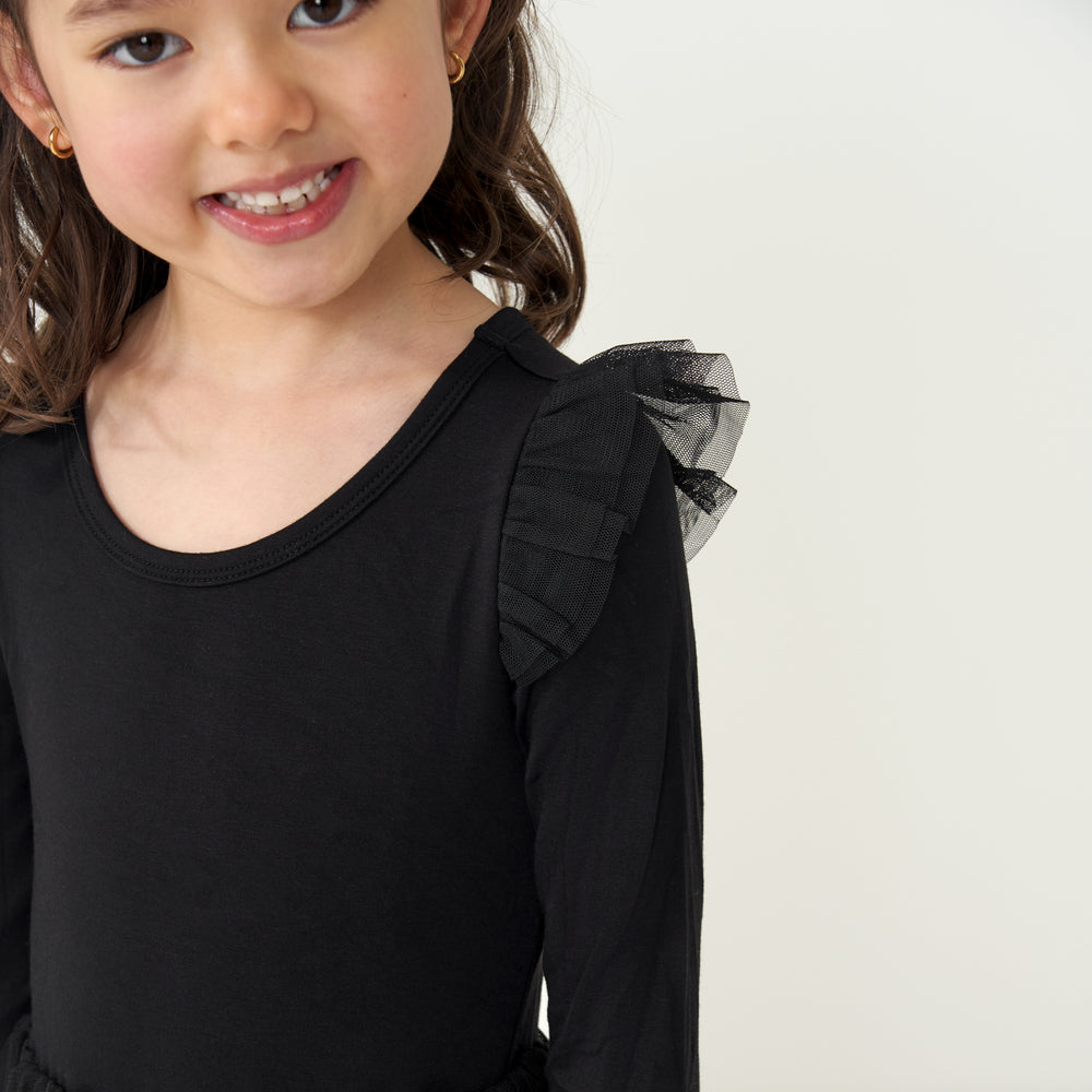 Close up image of a child wearing a Black flutter tutu dress detailing the flutter sleeve