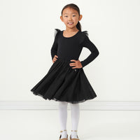 Child standing with her hands on her hips wearing a Black flutter tutu dress