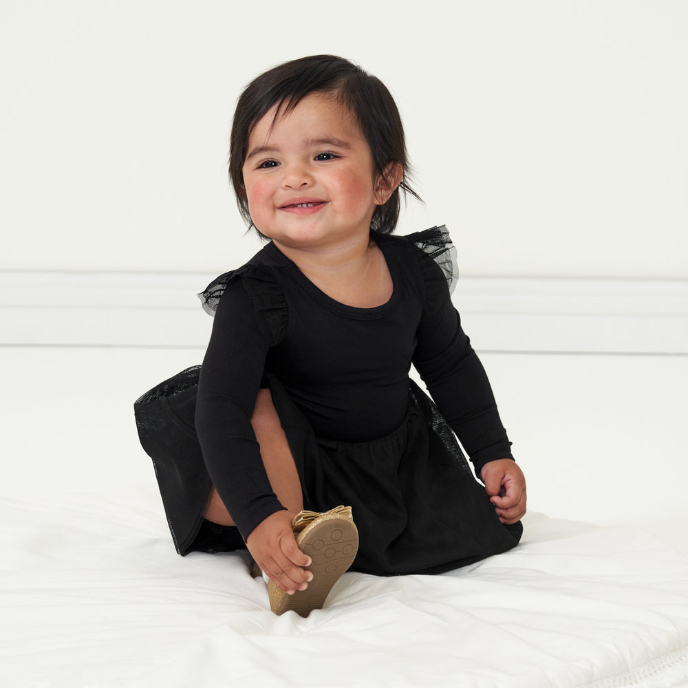 Child sitting on the ground wearing a Black flutter tutu dress with bloomer