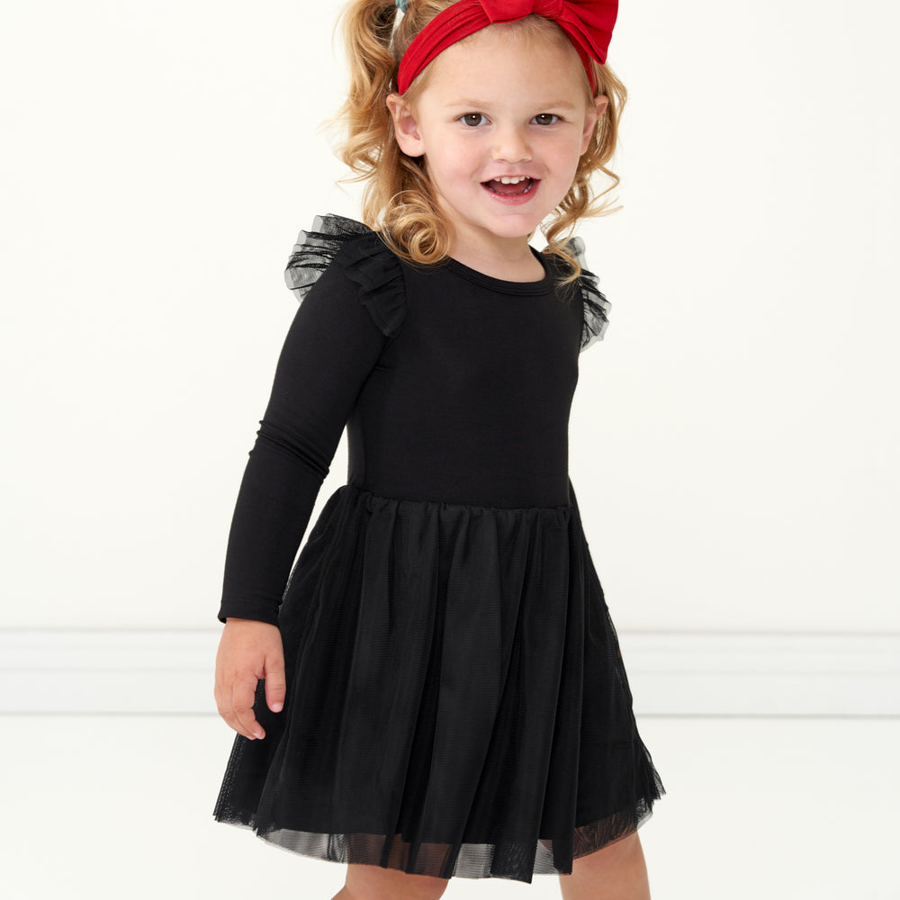 Child wearing a Black flutter tutu dress with bloomer and coordinating Holiday Red luxe bow headband