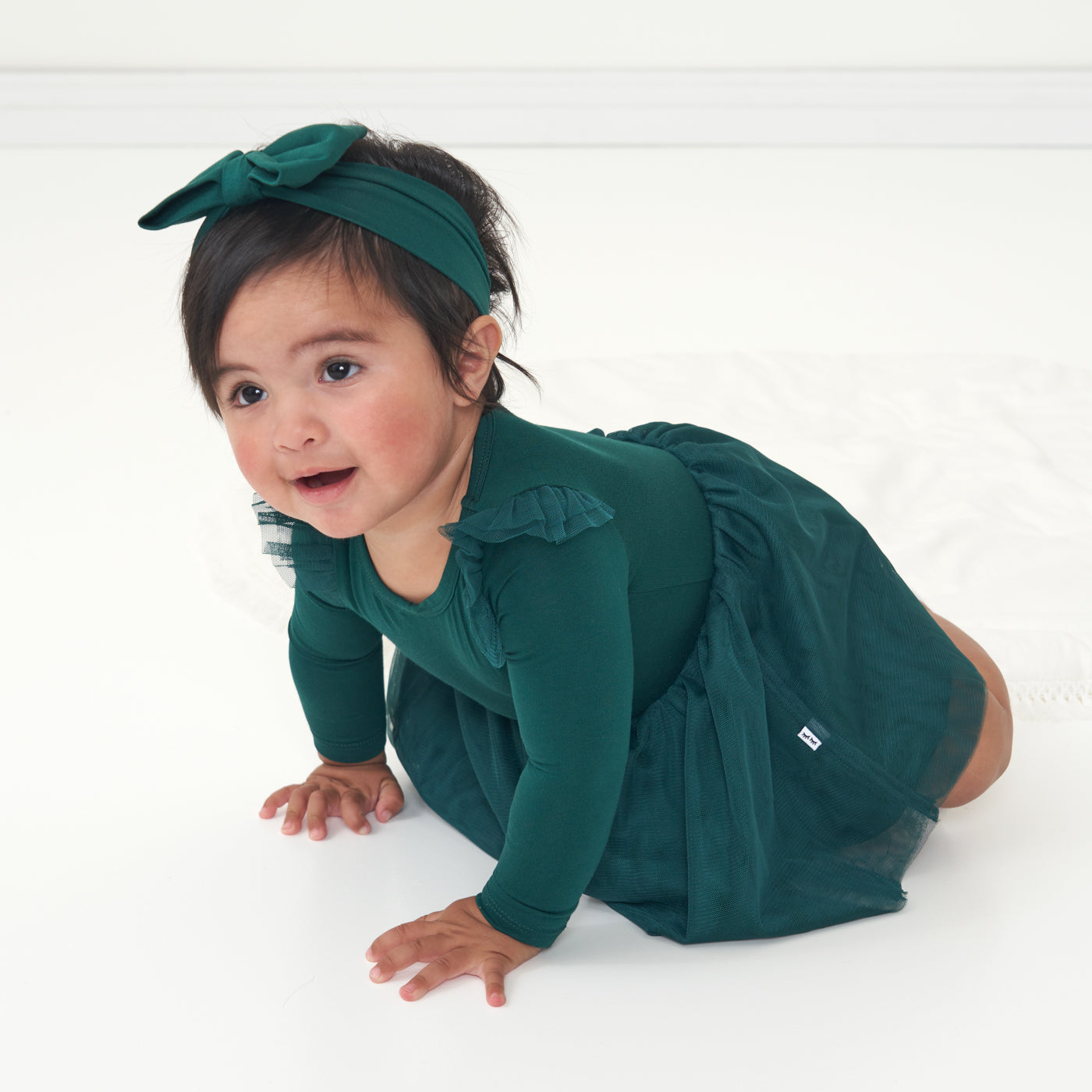 Child crawling wearing an Emerald flutter tutu dress with bloomer paired with an Emerald luxe bow headband