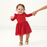 Child holding their mother's hand wearing a Holiday Red flutter tutu dress with bloomer