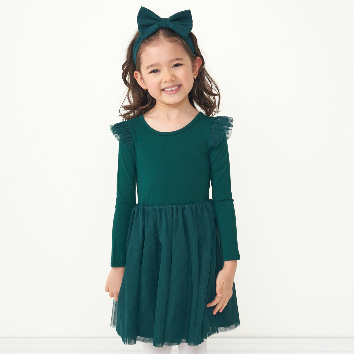 Child wearing an Emerald flutter tutu dress paired with an Emerald luxe bow headband