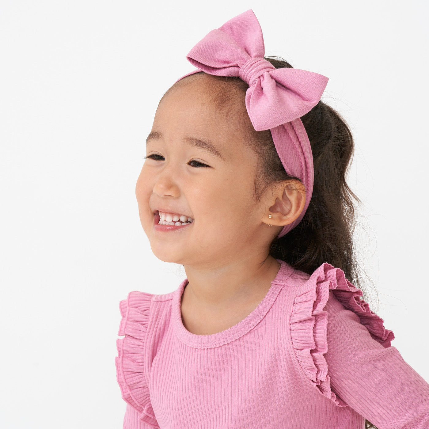 Profile image of a child wearing a Garden Rose luxe bow headband paired with a ribbed Garden Rose flutter tee