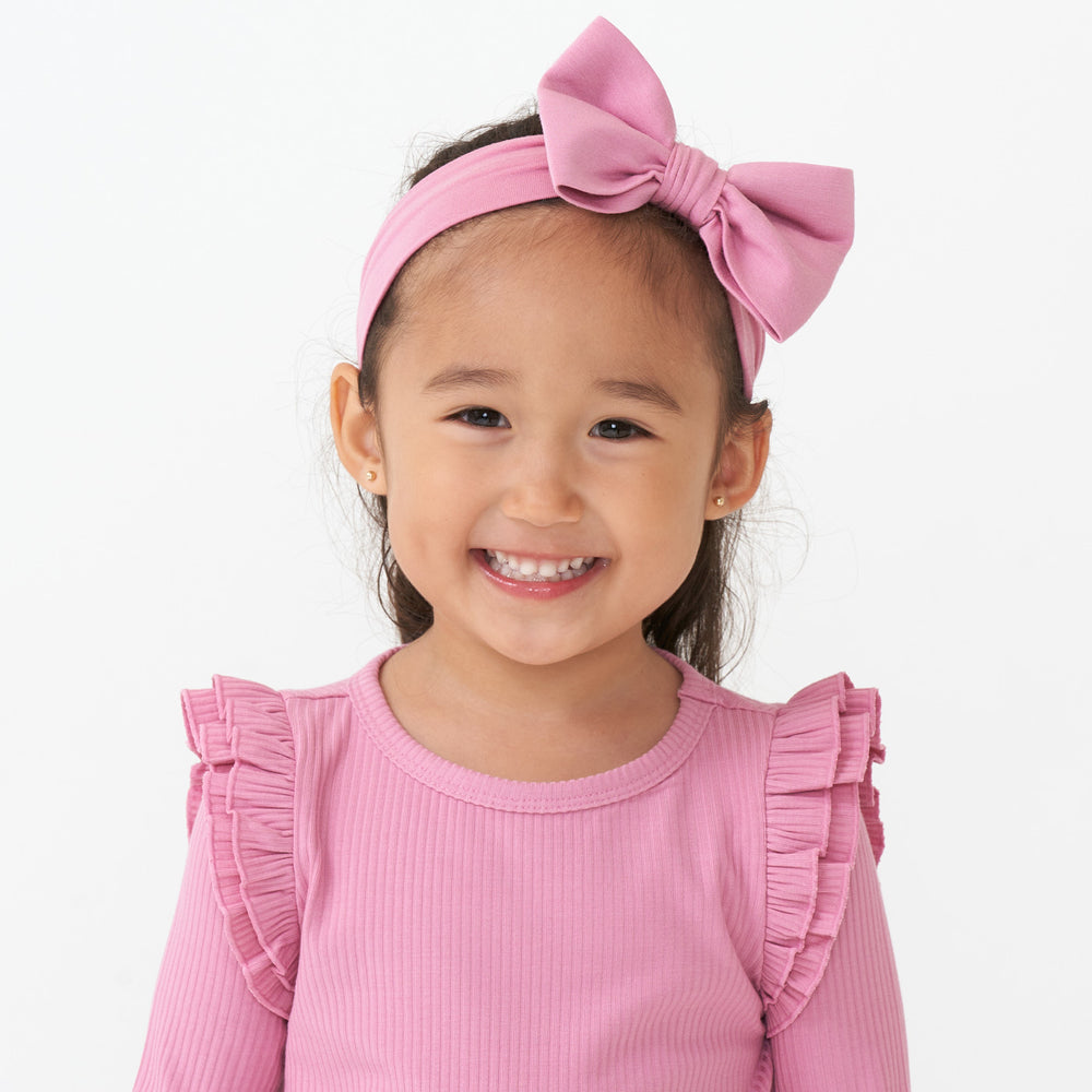 Close up image of a child wearing a Garden Rose luxe bow headband paired with a ribbed Garden Rose flutter tee 