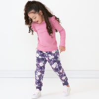 Child posing wearing a Garden Rose ribbed flutter tee paired with Sugar Plum Floral leggings