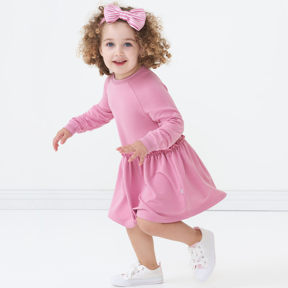 Child playing wearing a Garden Rose drop waist dress paired with a Garden Rose Stripe luxe bow headband