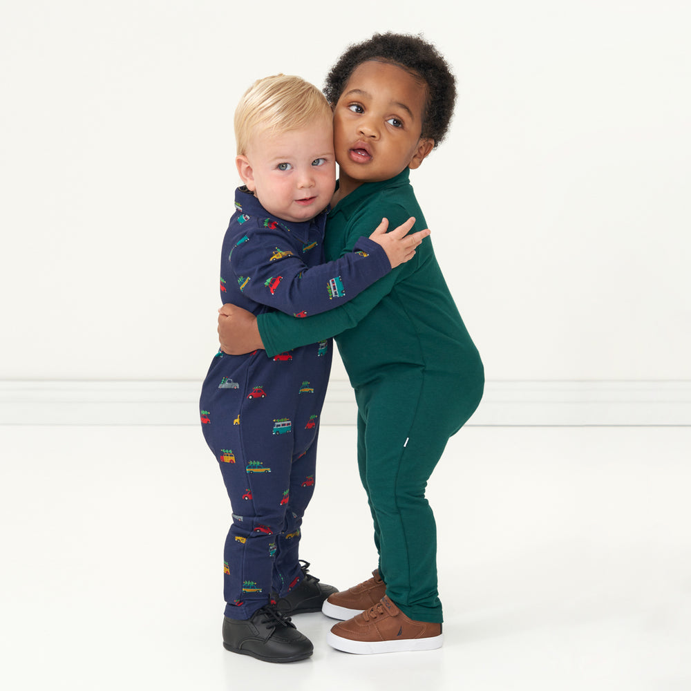 Two children hugging. One is wearing a Tree Traffic polo romper and the other child is wearing a Emerald polo romper