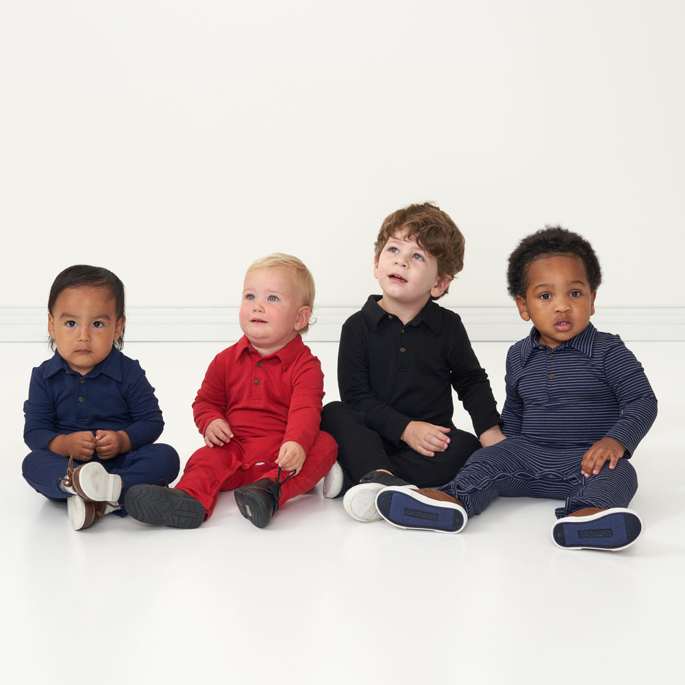 Four children sitting together wearing coordinating Holiday play polo rompers in the following prints: Sapphire, Holiday Red, Navy Stripes, Black