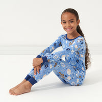 Profile view of a child sitting wearing Hanukkah Lights and Love two piece pajama set