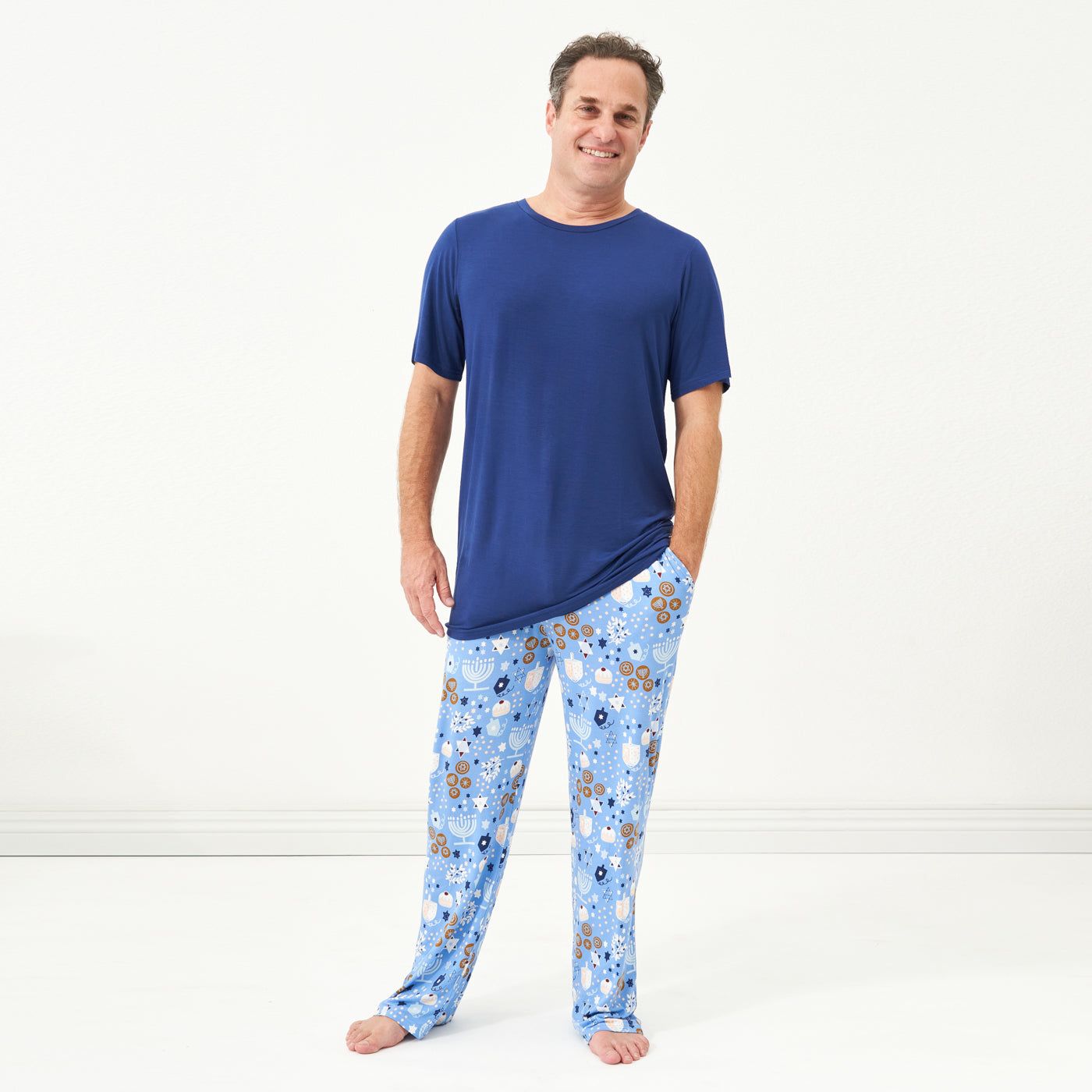 Man posing wearing a Hanukkah Lights and Love men's pajama pants paired with a men's Sapphire short sleeve pajama top
