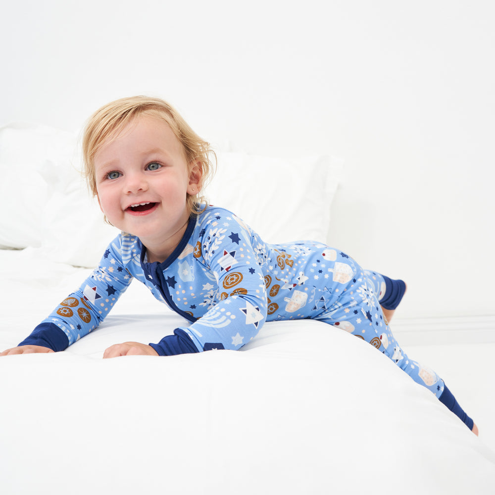 Child laying on a bed wearing Hanukkah Lights and Love zippy