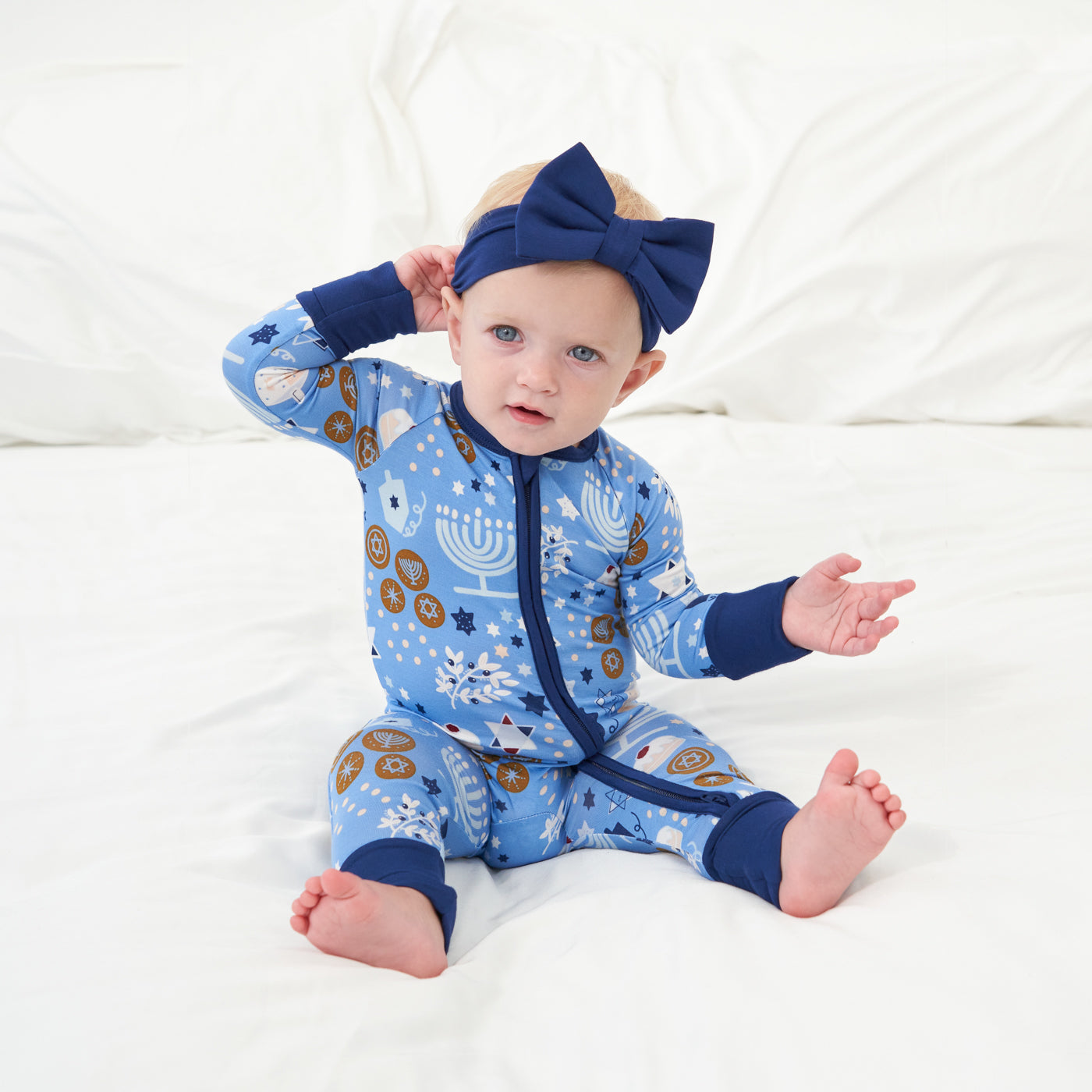 Child wearing a Hanukkah Lights and Love zippy paired with a Sapphire luxe bow headband