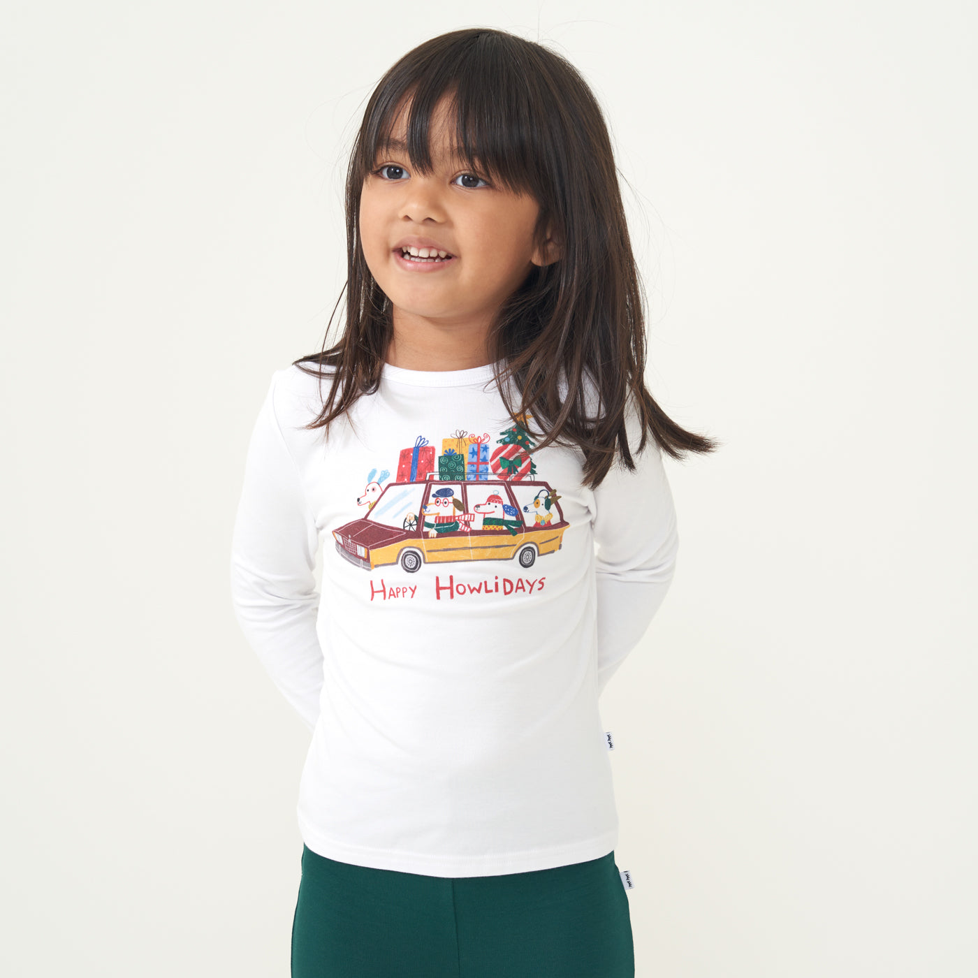 Child wearing a Happy Howlidays graphic tee with her hands behind her back