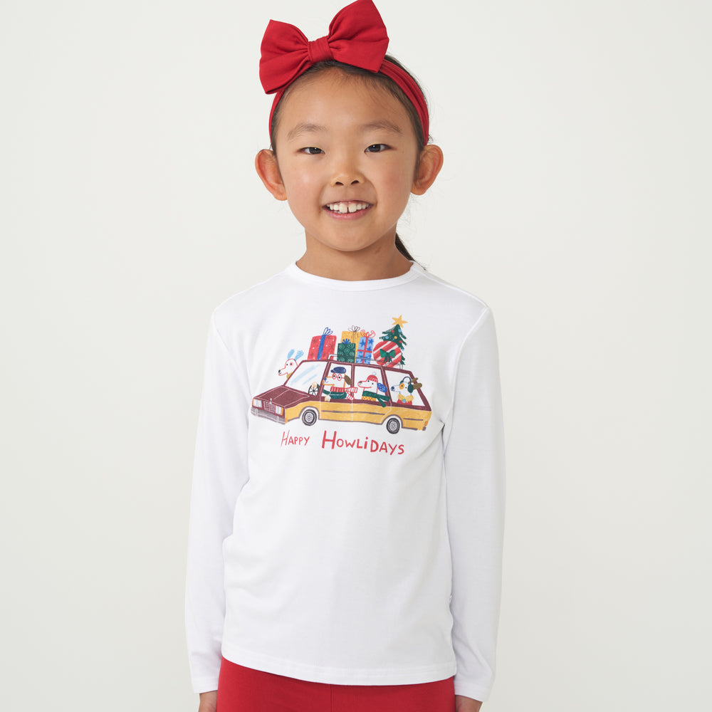 Child wearing a Happy Howlidays graphic tee and coordinating Holiday Red luxe bow headband