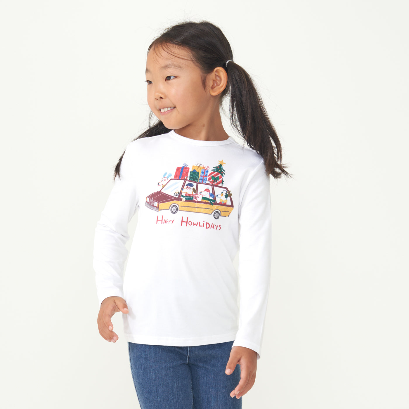 Child looking to the side wearing a Happy Howlidays graphic tee