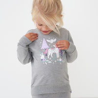 Close up image of a child wearing a Unicorn crewneck sweatshirt detailing the unicorn graphic