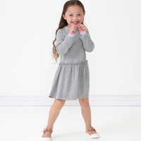 Child posing wearing a Heather Gray drop waist dress