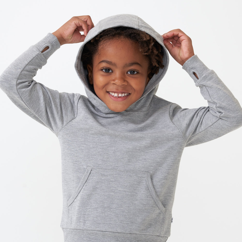 Child posing wearing a Heather Gray pullover hoodie with the hood on his head