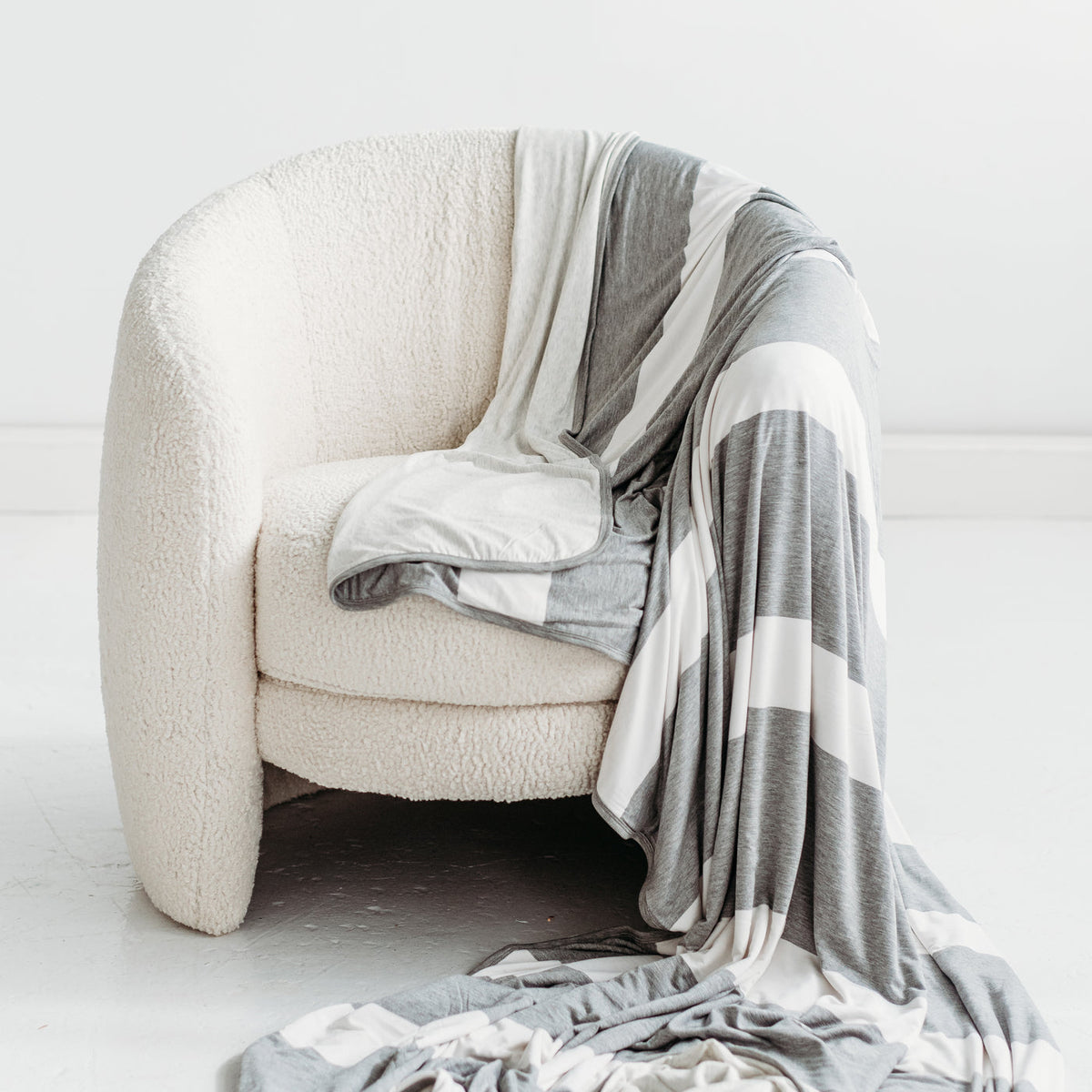 Heather Gray Stripe oversized bamboo blanket draped over the side of a chair.