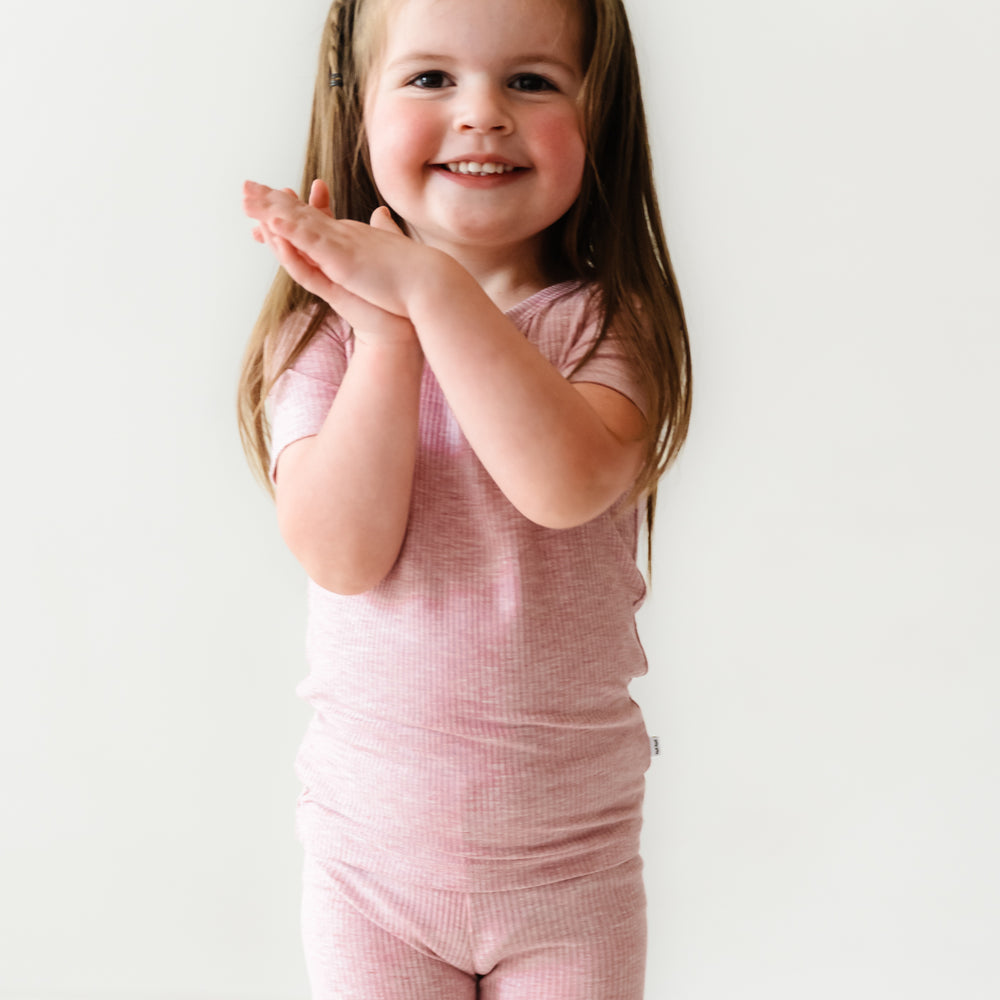 Click to see full screen - Child posing wearing Heather Mauve Ribbed two piece short sleeve and shorts pajama set
