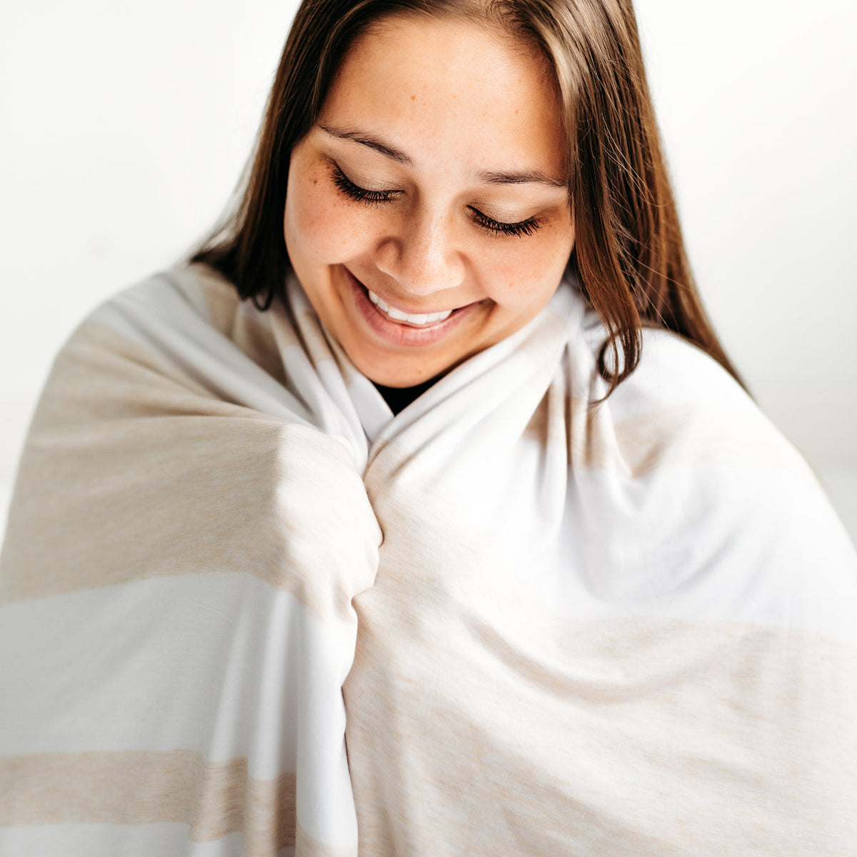 Close up of a woman wrapped up in a Heather Oatmeal Stripe oversized bamboo blanket