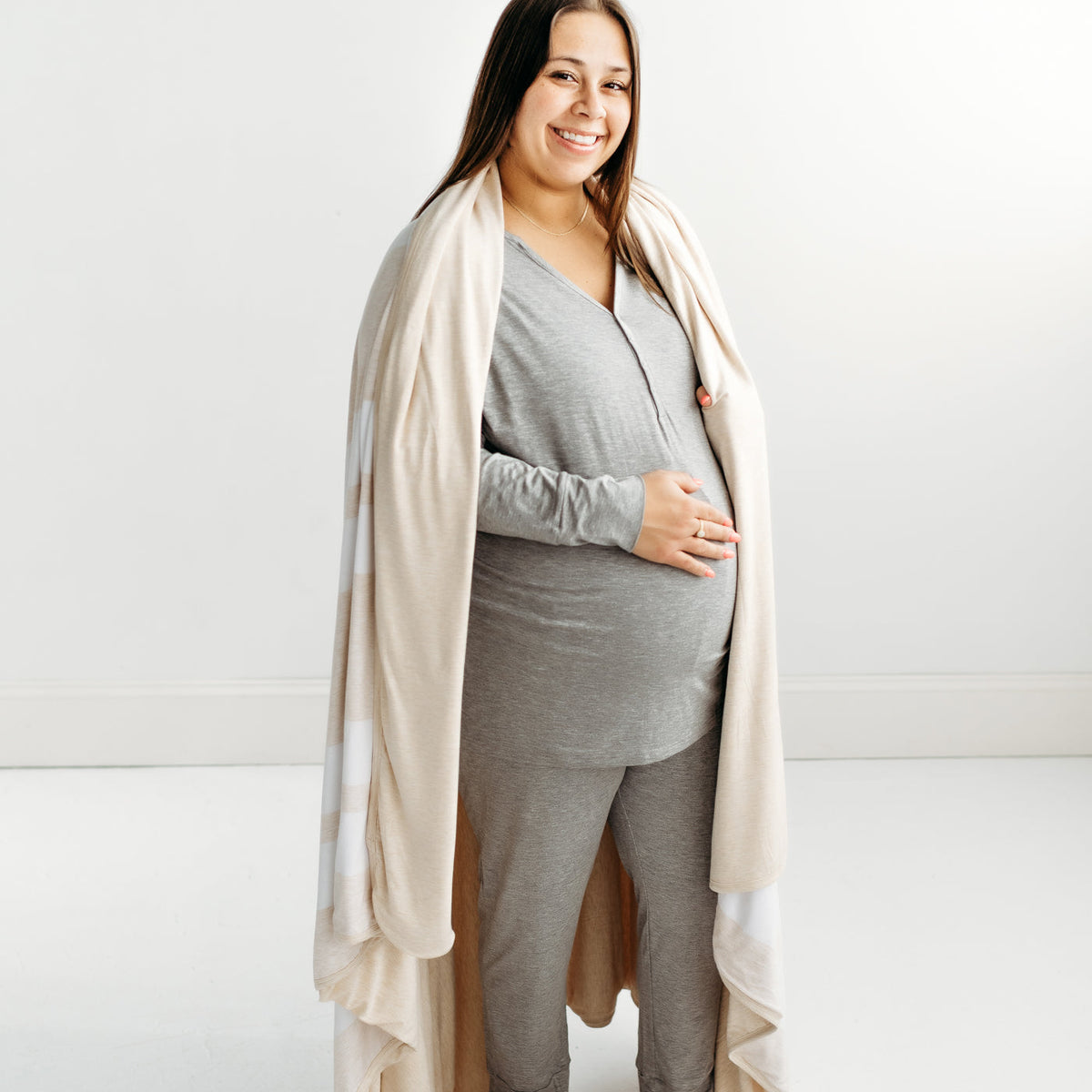 Pregnant woman with a Heather Oatmeal Stripe oversized bamboo blanket draped around her shoulders