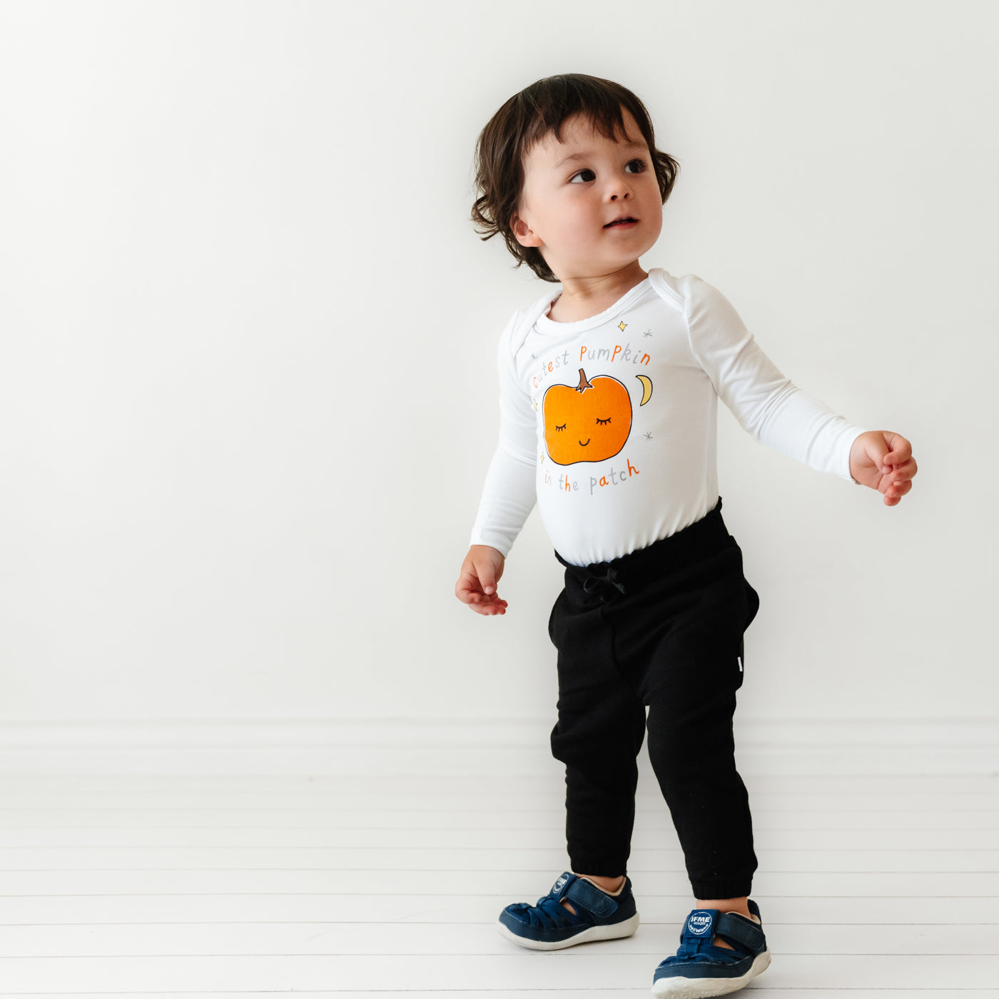 Child wearing a Little Pumpkin graphic bodysuit paired with Black Paperbag joggers