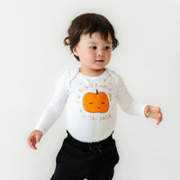 Close up image of a child wearing a Little Pumpkin graphic bodysuit paired with Black Paperbag joggers